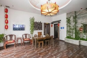 A hotel lobby with a dining area, a television, and decorative plants. - Harbin Cashbox Express Hotel (Harbin)