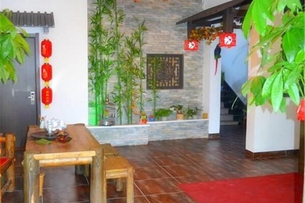 A dining area with a wooden table and chairs, a stone wall, and bamboo plants.