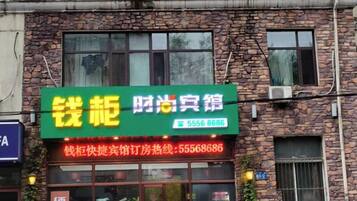 A brick building with a green signboard displaying a phone number.