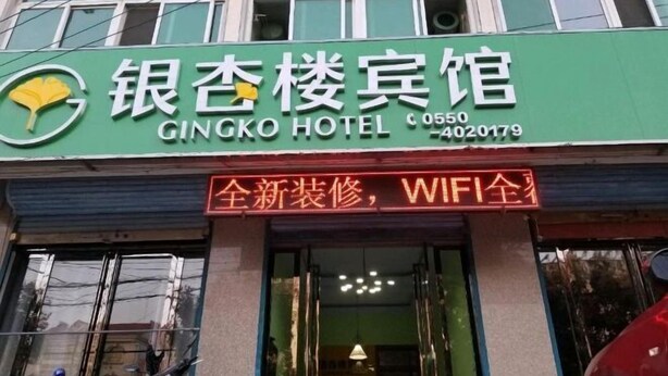 En hotellskylt med en grön och vit färgskala, som visar en logotyp och namnet ”GINGKO HOTEL”.