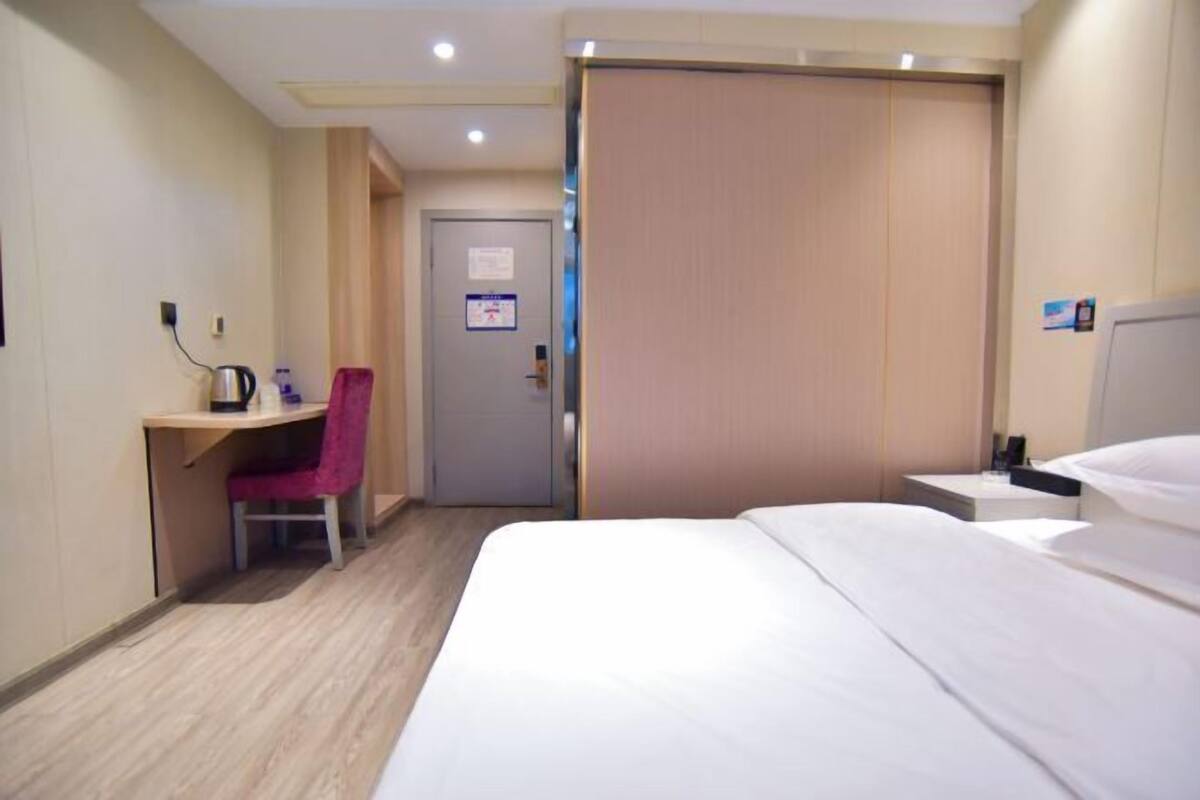 A hotel room with a bed, a desk, a chair, and a wardrobe.