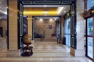 Un vestíbulo de hotel con una mesa de recepción, una escalera y un globo decorativo.