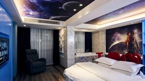 A bedroom with a bed, a chair, a vanity with a mirror, and a wall mural of a space scene. - WP Guo Creative Hotel (Cangnan EMU Station Store) (Cangnan)