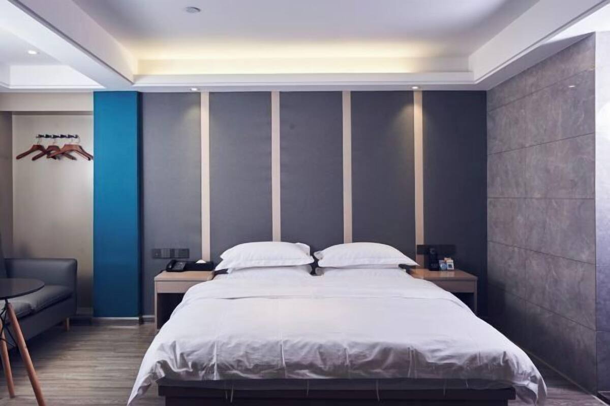 A modern hotel room with a large bed, bedside tables, a desk, and a chair.