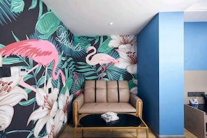 A room with a floral mural, a beige sofa, a black coffee table, and a blue accent wall.