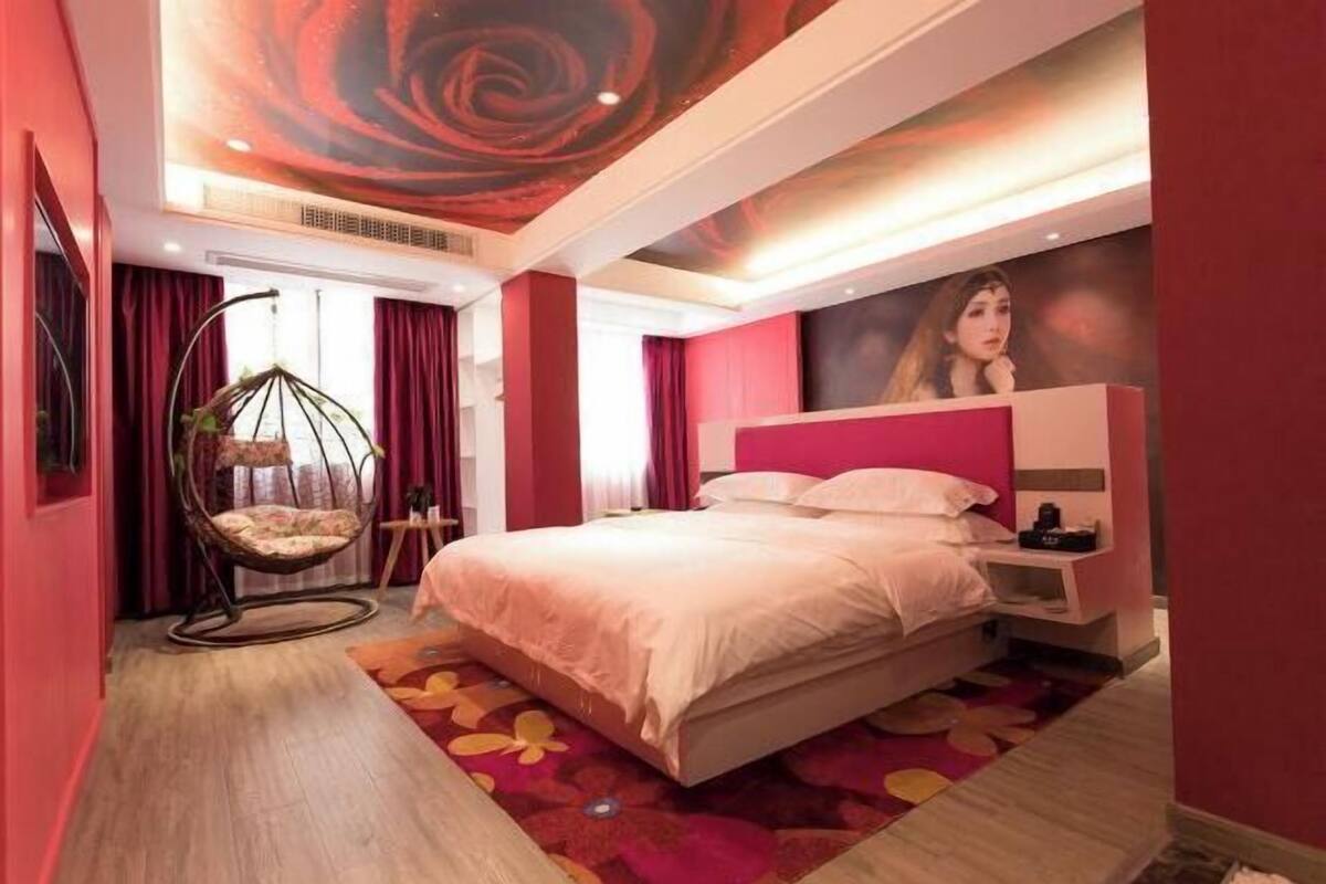 A modern hotel room with a large bed, a hanging chair, and a vibrant floral carpet.