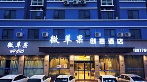 A hotel facade with multiple air conditioning units, a signboard with Chinese characters, and several parked cars in front. - WP Guo Creative Hotel (Cangnan EMU Station Store) (Cangnan)