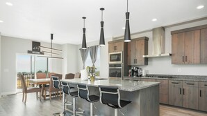 Una cocina moderna con una isla central, taburetes de bar y un comedor con vistas.