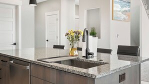 Una cocina moderna con encimera de granito, electrodomésticos de acero inoxidable y grifo negro.