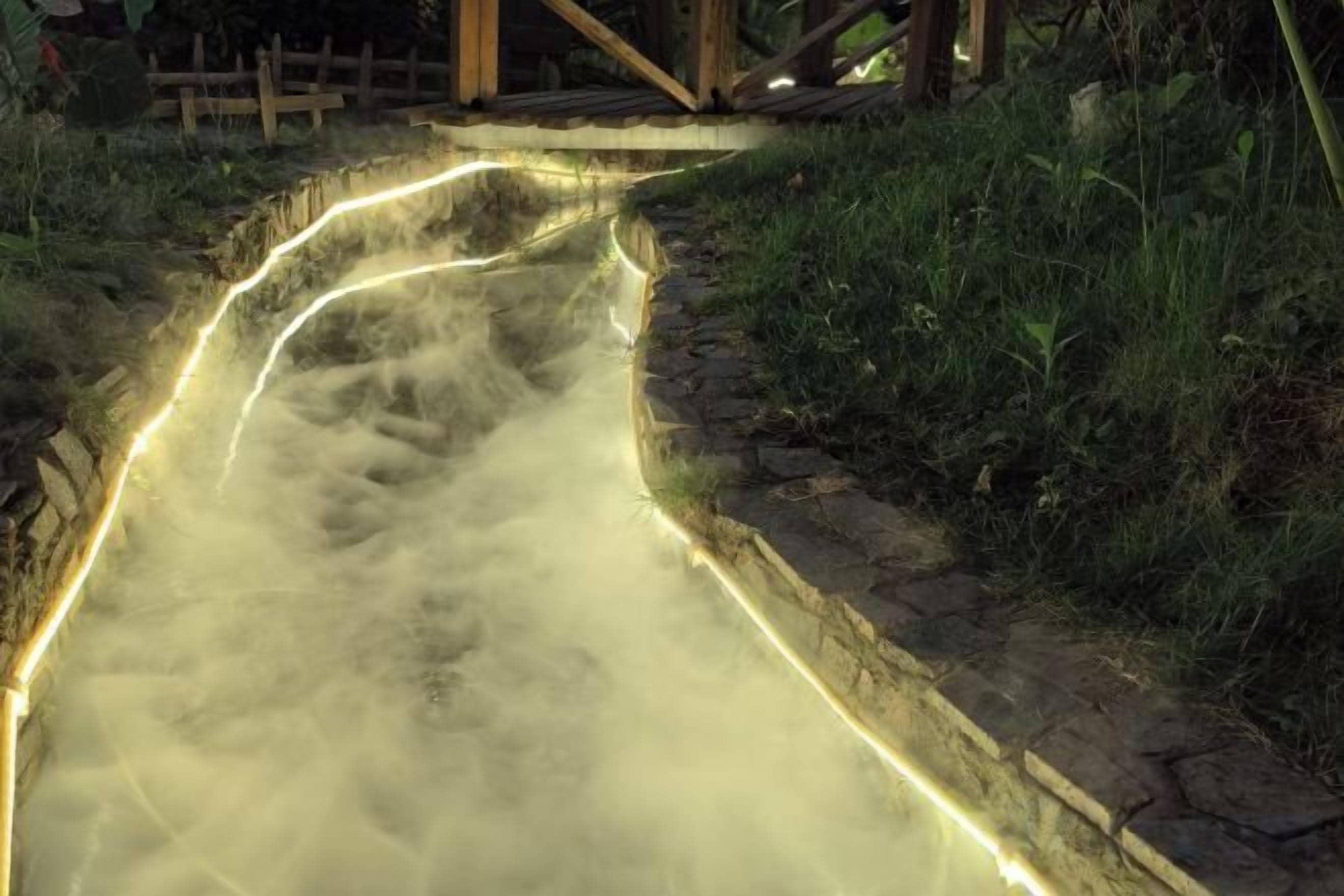 Een pad met verlichte randen, omgeven door gras en een stenen rand.