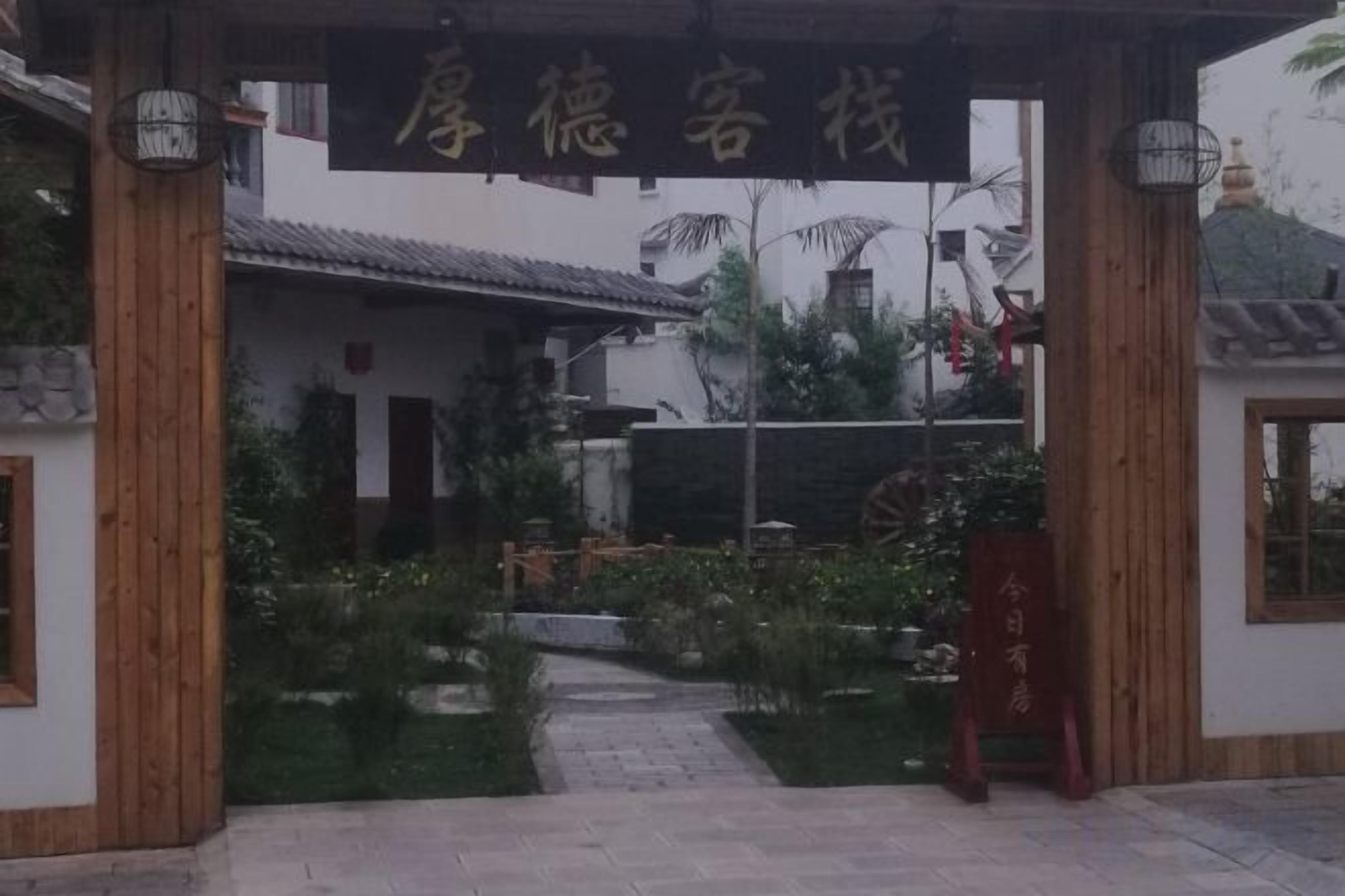 Un edificio chino tradicional con un letrero, una entrada de madera y un jardín.