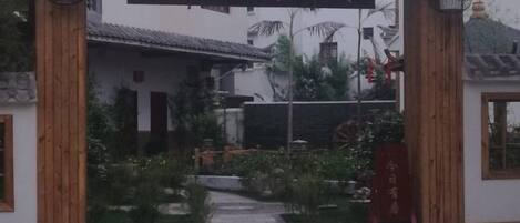 Un edificio chino tradicional con un letrero, una entrada de madera y un jardín.
