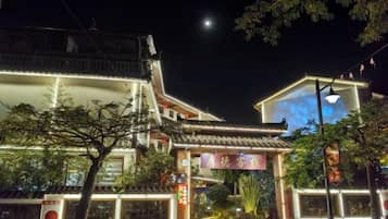 Ein traditionelles Gebäude mit Ziegeldach, beleuchtetem Eingang und einem Schild mit chinesischen Schriftzeichen.