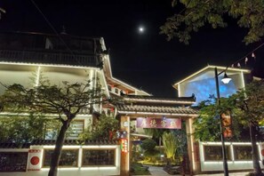 Un bâtiment traditionnel avec un toit en tuiles, une entrée illuminée et une enseigne avec des caractères chinois.