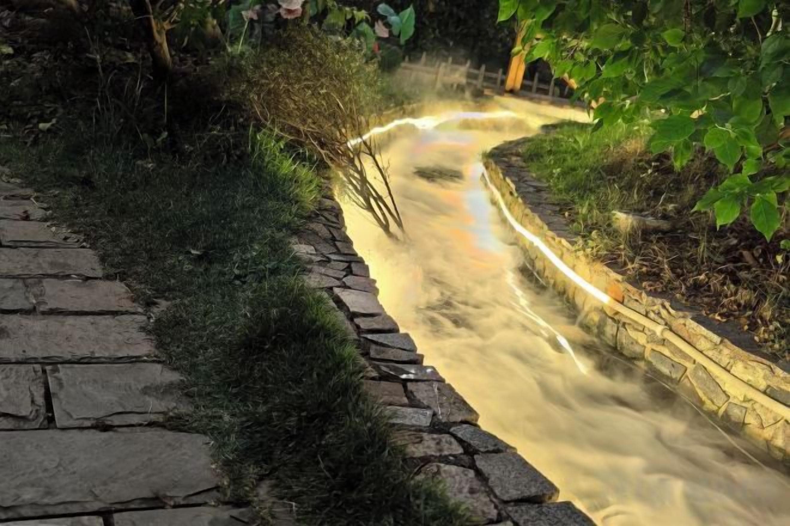 A stone pathway leading to a water feature with a curved design.