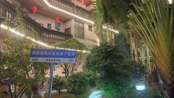 Ein Gebäude mit einer chinesischen Beschilderung, umgeben von Grünpflanzen und beleuchtet mit Lichterketten.