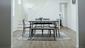 Un coin repas avec une table et des bancs, un escalier et une petite plante posée sur la table.