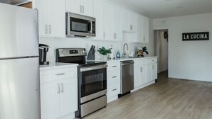Une cuisine moderne avec des armoires blanches, des appareils en acier inoxydable et une enseigne portant l’inscription « LA CUCINA ».