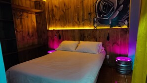A bedroom with a wooden headboard, a bed with white bedding, and a wall-mounted abstract art piece. - Hotel Velero Sur (Iquique)