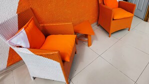 A room with a white wicker sofa and armchair, both with orange cushions, and a matching orange table. - Hotel Velero Sur (Iquique)