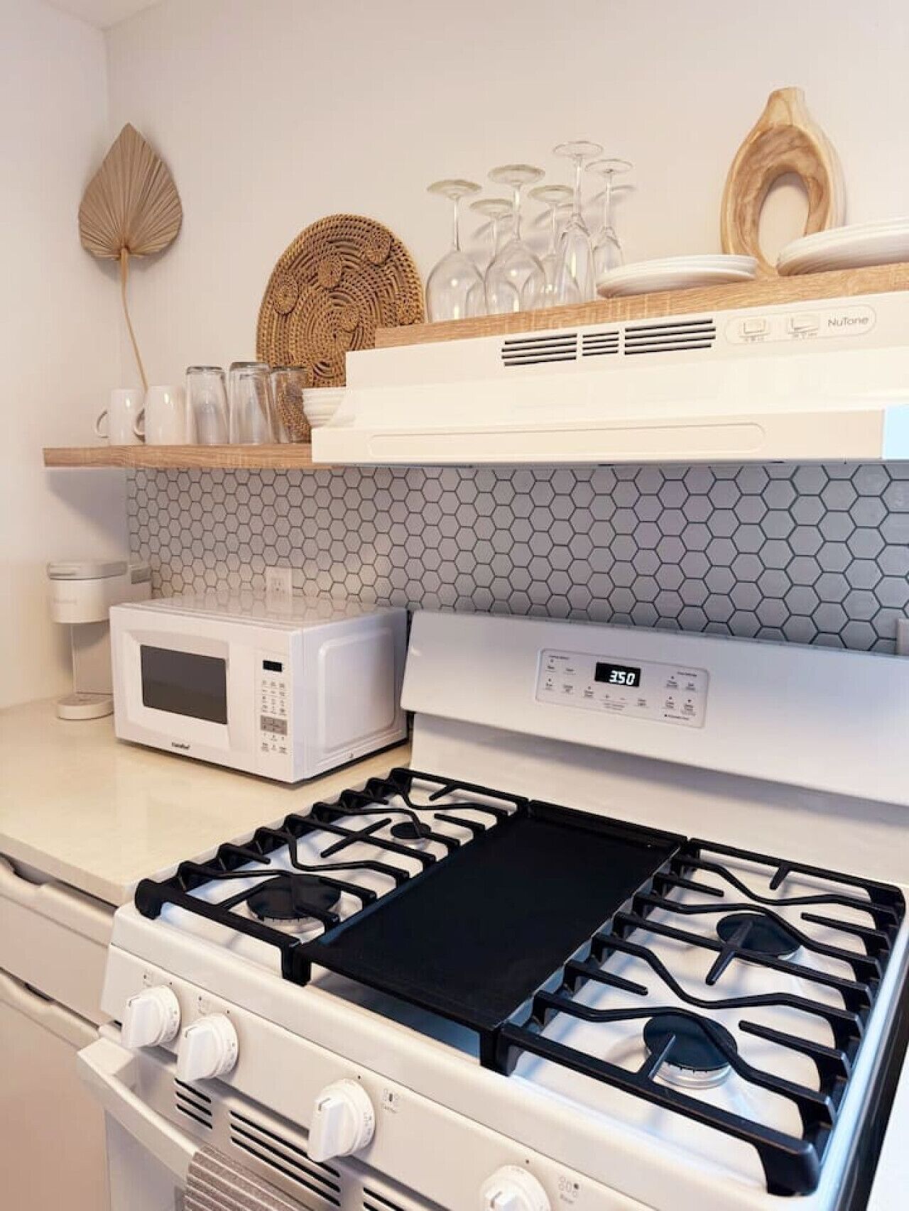 Cozinha com fogão a gás, micro-ondas e coifa NuTone.