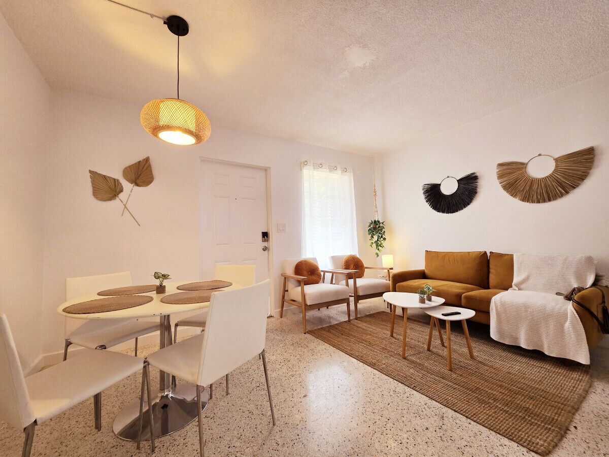 A modern living room with a dining area, featuring a sofa, coffee table, and a dining table with chairs.