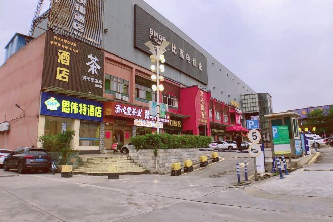 Un edificio a più piani con diversi esercizi commerciali al piano terra, tra cui un hotel, un ristorante e un negozio.