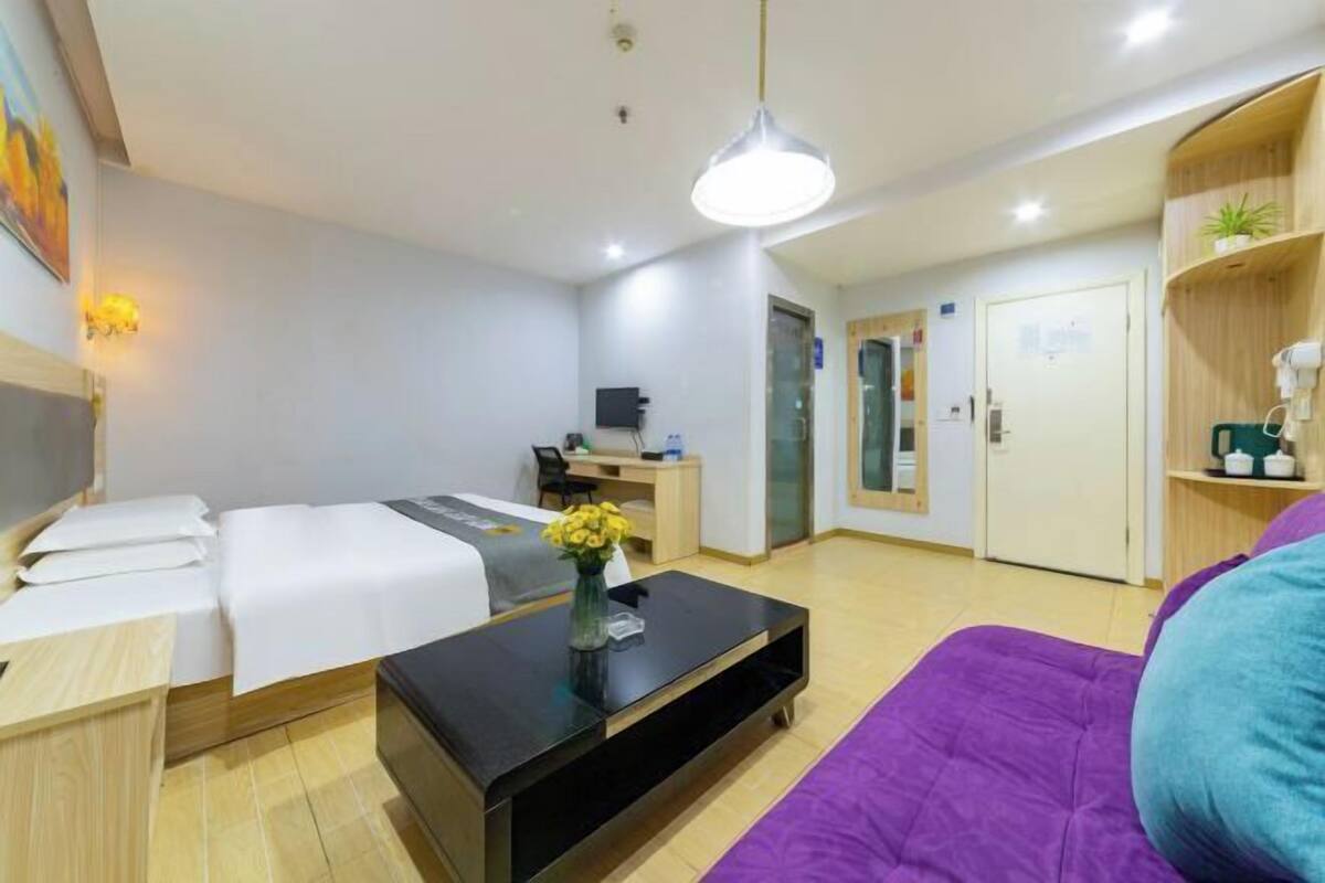 Hotellihuone, jossa on kaksi sänkyä, työpöytä, tietokone, kahvinkeitin ja televisio.
