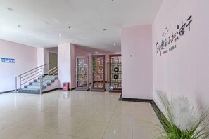 Rebedor d'hotel amb una escala, una taquilla d'hostes i panells decoratius.