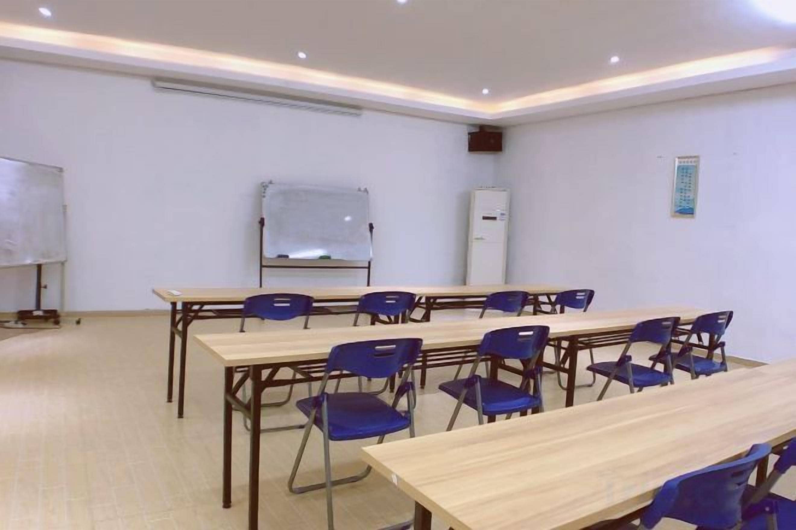 A conference room with a whiteboard, a projector, and a refrigerator.
