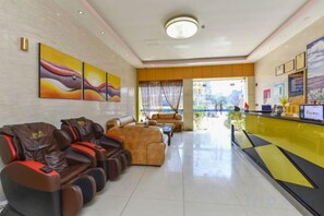 A hotel lobby with a reception desk, seating area with massage chairs, and artwork on the walls. - SWT(sweetheart) Express Hotel (Dongguan)
