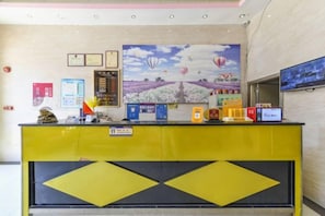 A reception desk with a yellow and black design, a large painting of hot air balloons, and various informational posters. - SWT(sweetheart) Express Hotel (Dongguan)
