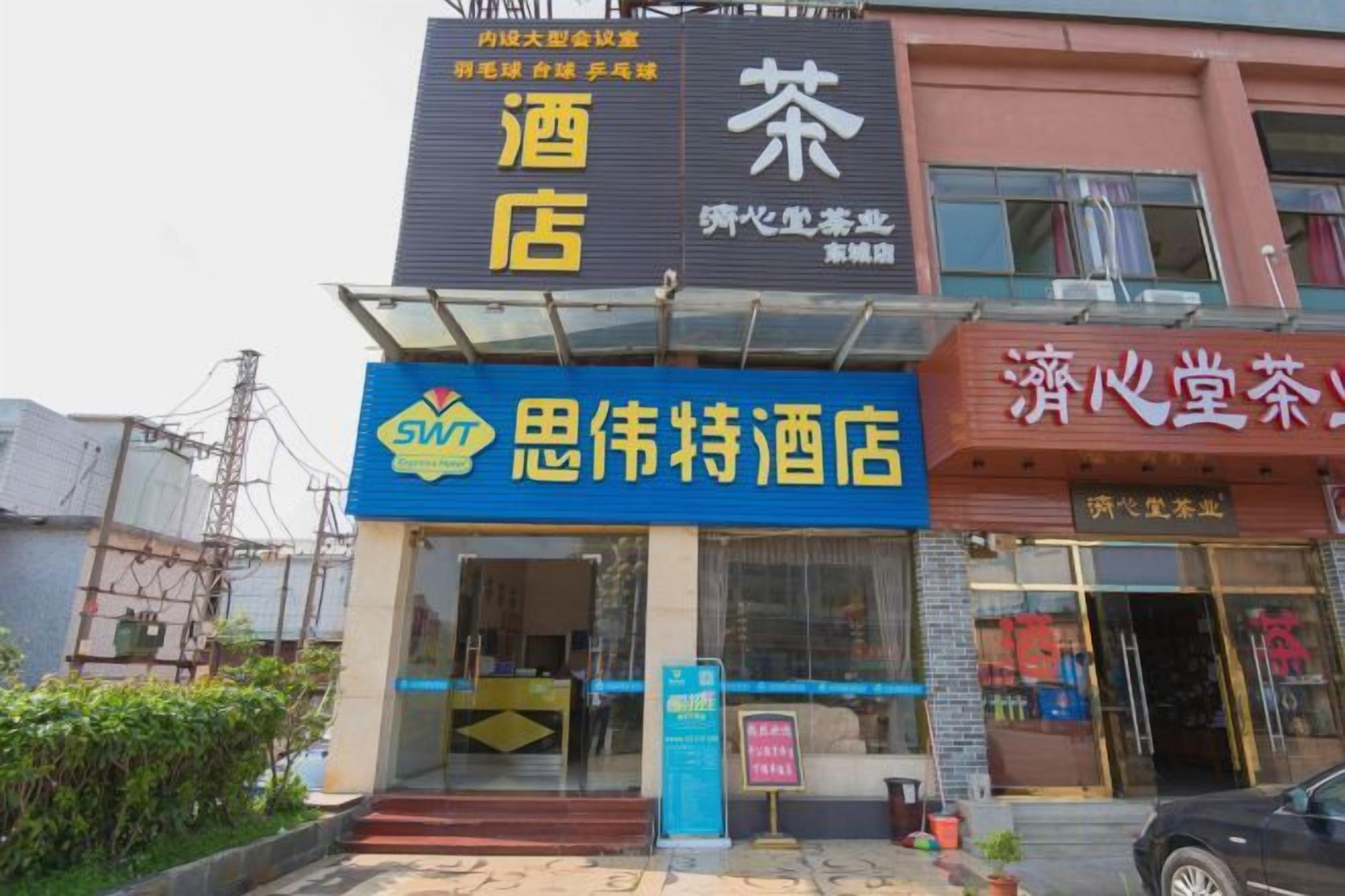 A hotel with a prominent SWT logo, a visible entrance, and a signboard with Chinese characters.