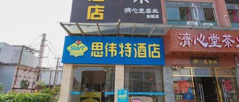 A hotel with a prominent SWT logo, a visible entrance, and a signboard with Chinese characters.