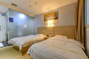 A hotel room with two beds, a wooden headboard, a wall-mounted light, and a door leading to a bathroom. - SWT(sweetheart) Express Hotel (Dongguan)