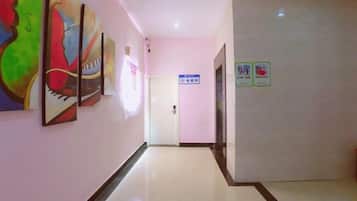 A hallway with a door at the end, a sign on the wall, and artwork on the left.