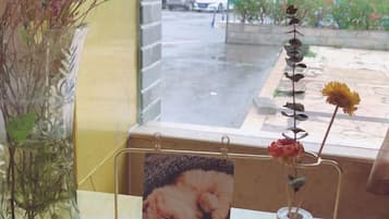 Una ventana con un jarrón de flores secas y un marco de fotos sobre una mesa.
