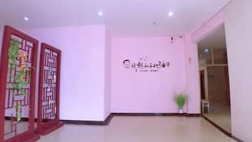 A reception area with a wall-mounted sign, a decorative screen, and a potted plant.