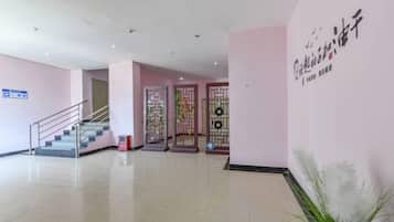Un vestíbulo de hotel con una escalera, un mostrador de recepción y una pared decorativa.