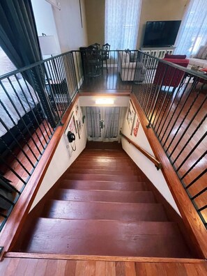 A wooden staircase with metal railings leading to an upper floor.