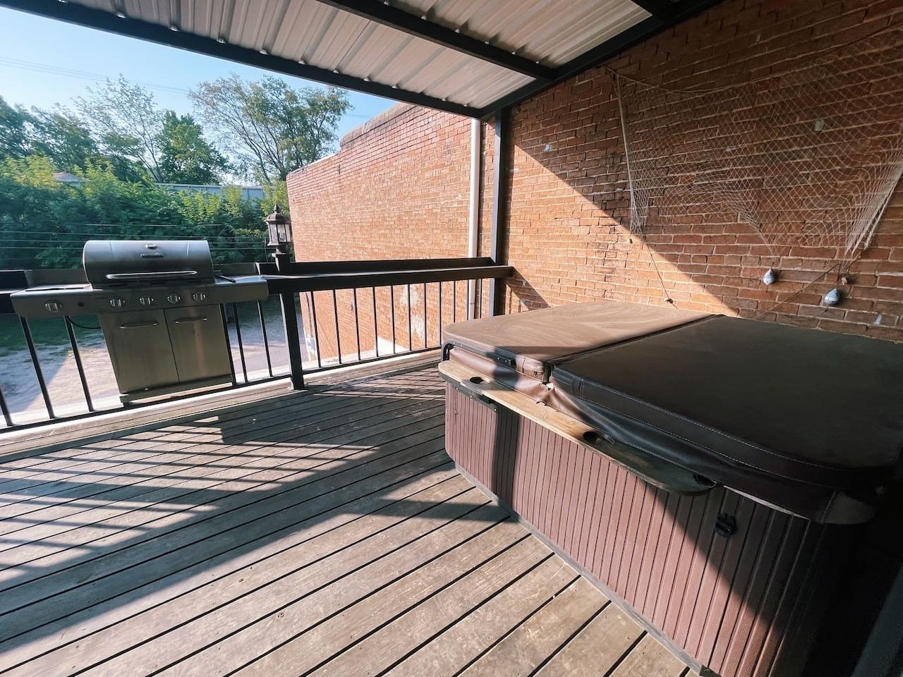 Une terrasse extérieure équipée d’un barbecue, d’un bain à remous et d’un plancher en bois.