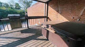 Une terrasse extérieure équipée d’un barbecue, d’un bain à remous et d’un plancher en bois.
