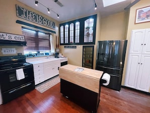 A kitchen with a black stove, white cabinets, a wooden countertop, and a black refrigerator. - The Landing at Main Street Suites (Van Buren)