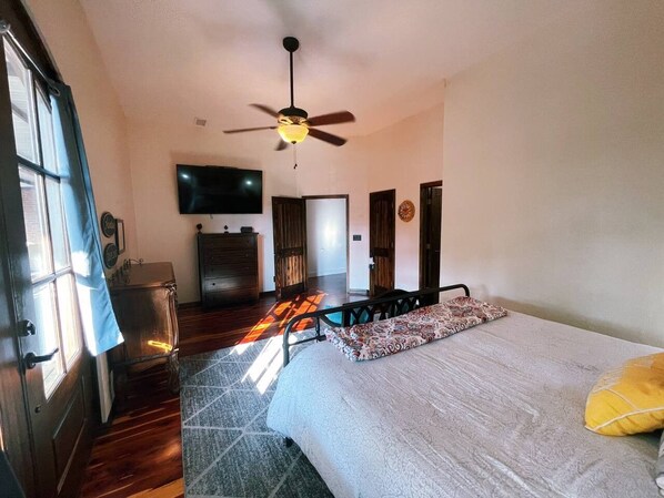 A bedroom with a bed, a ceiling fan, a television, and a wardrobe.