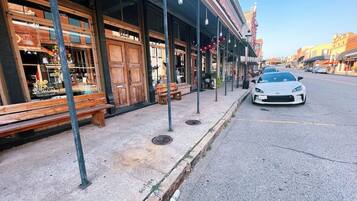 Une rue bordée de boutiques, avec un banc et une voiture garée.