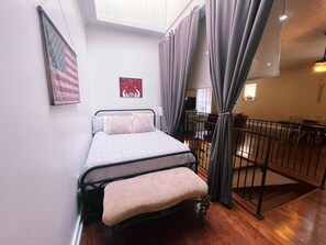 Ein Schlafzimmer mit Bett, Vorhängen, einem Fenster und Blick auf einen Balkon.