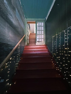 A staircase with red steps leading to a door, surrounded by walls with string lights. - The Landing at Main Street Suites (Van Buren)