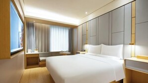 A modern hotel room with a large bed, a bedside table, a nightstand, a TV, and a window with curtains. - JI Hotel (Beijing South Railway Station Jiaomen East Subway Station) (Beijing)