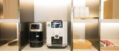 Une machine à café et un distributeur d’eau sont posés sur une étagère dans une chambre d’hôtel.
