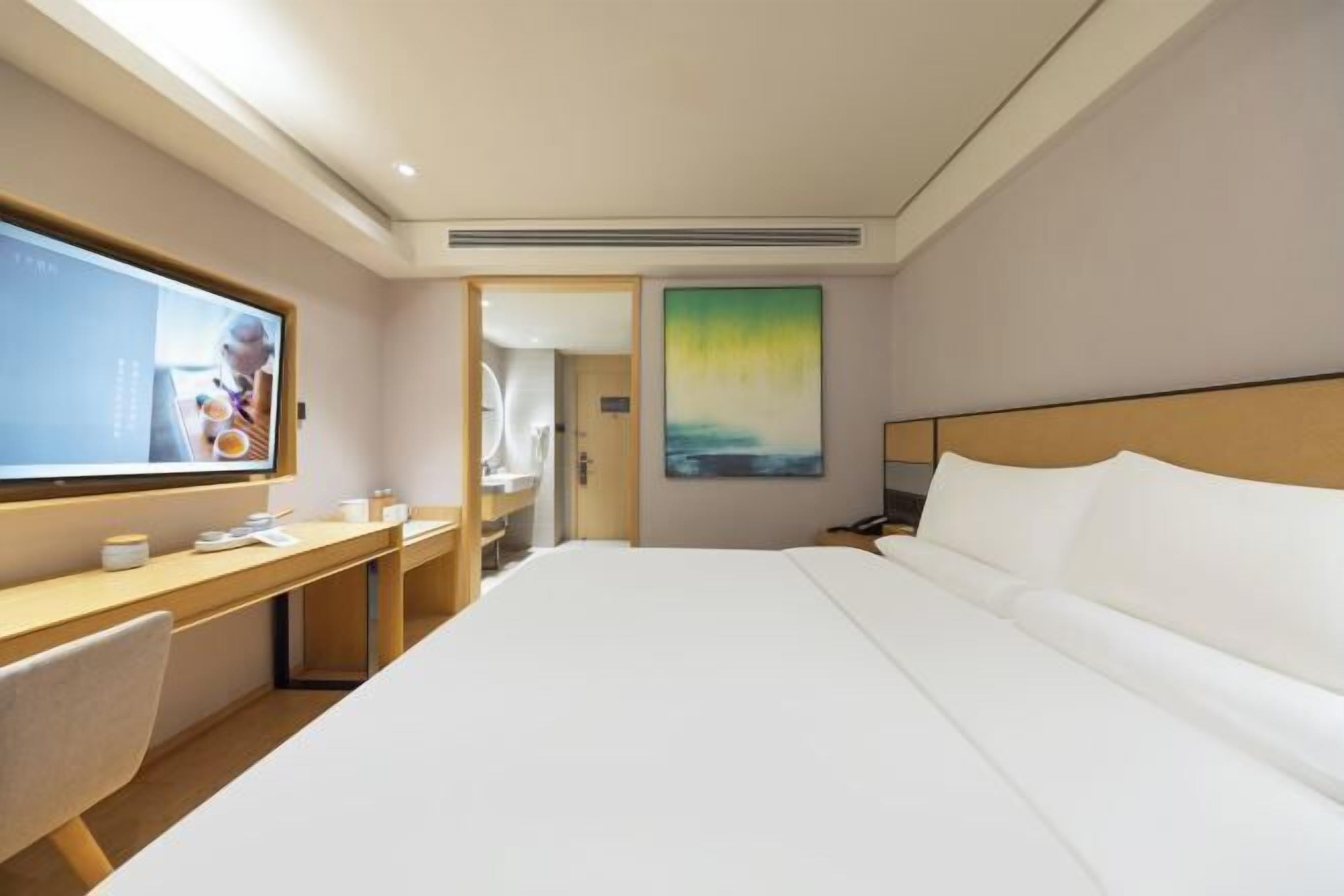 Habitación de hotel con cama, escritorio, televisión y un cuadro en la pared.